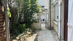Un estrecho callejón que conduce a un edificio con una verja de metal y una puerta de madera.