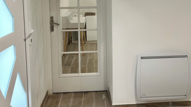 Una puerta blanca con paneles de vidrio esmerilado, suelo de baldosas y un radiador blanco en la pared.