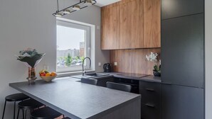 A modern kitchen with a large island, wooden cabinets, and a view of the city.