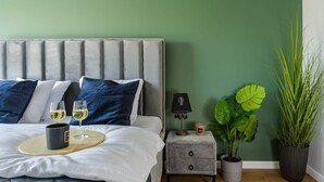 A bedroom with a bed, bedside table, and two potted plants. - Spacious apartment on Wróblewskiego (Łódź)