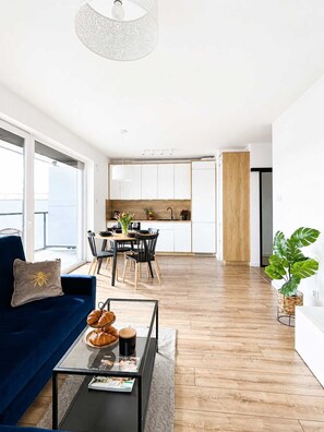Un salon moderne avec un canapé, une table basse et une vue sur la cuisine et la salle à manger.