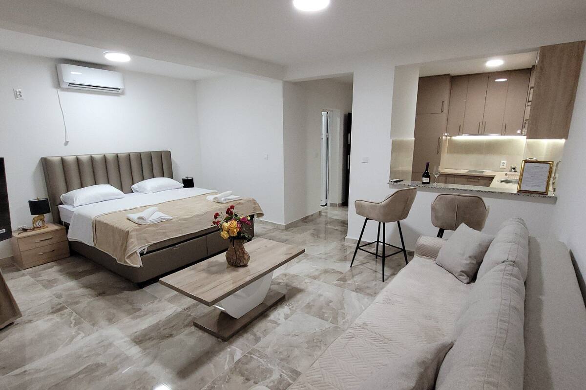 Et moderne hotelværelse med seng, sofa, et lille bord og et spejl.