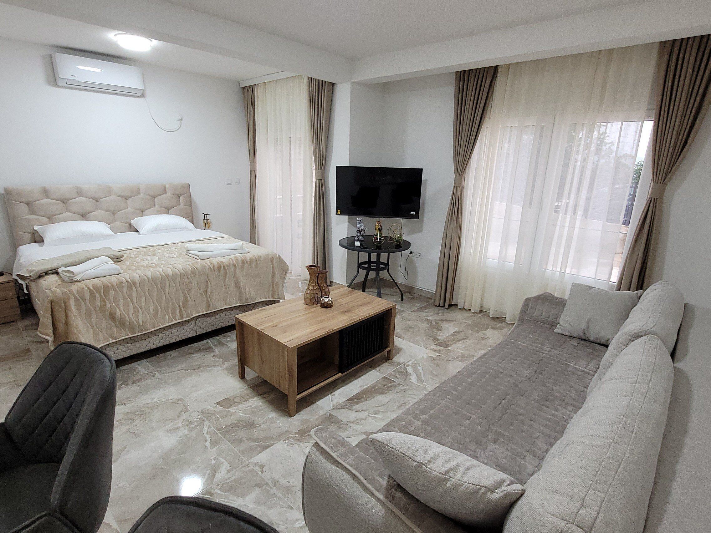 A hotel room with a bed, a sofa, a TV, and a small table.