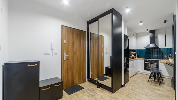 A modern kitchen with wooden cabinets, a black countertop, and a large mirror.