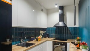 A modern kitchen with white cabinets, a black sink, and a stainless steel range hood.