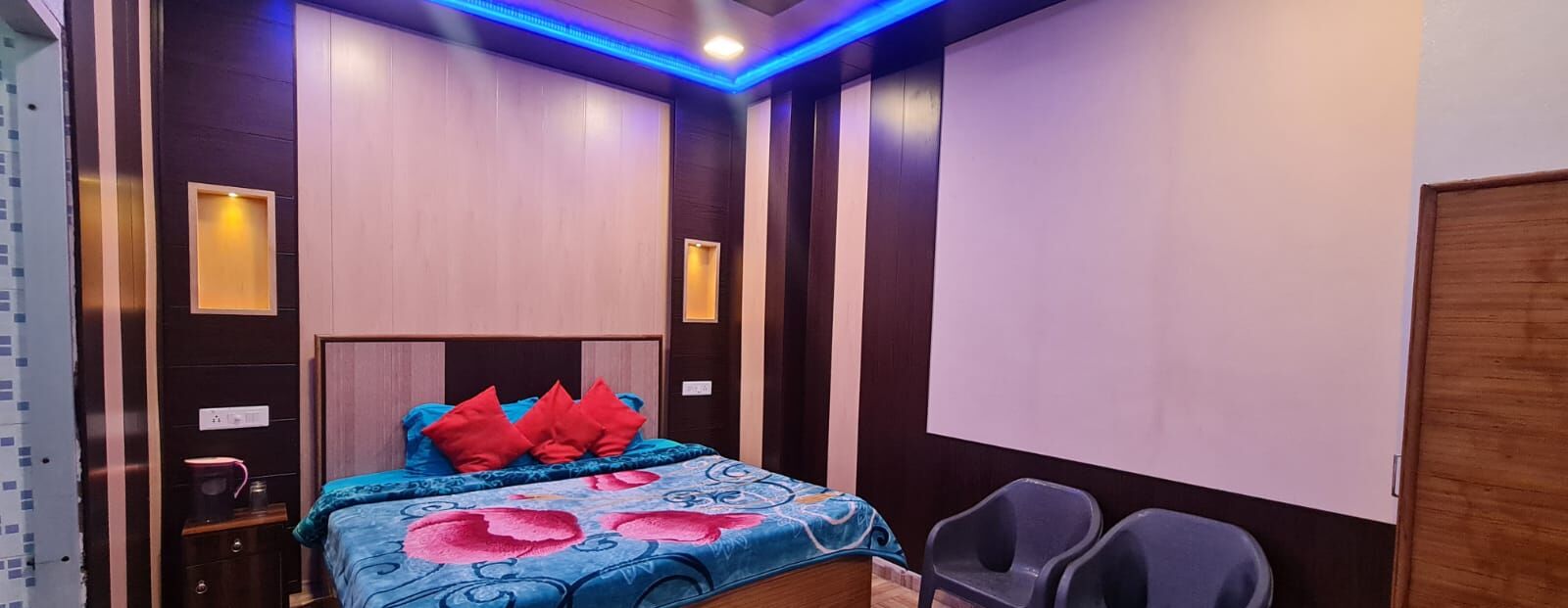 Un dormitorio con cama, dos mesitas de noche, un armario y una pequeña zona de estar con dos sillones.
