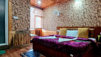 Une pièce avec un plafond en bois, un papier peint à motifs, un lit recouvert d’une couverture violette et une table de chevet en bois.