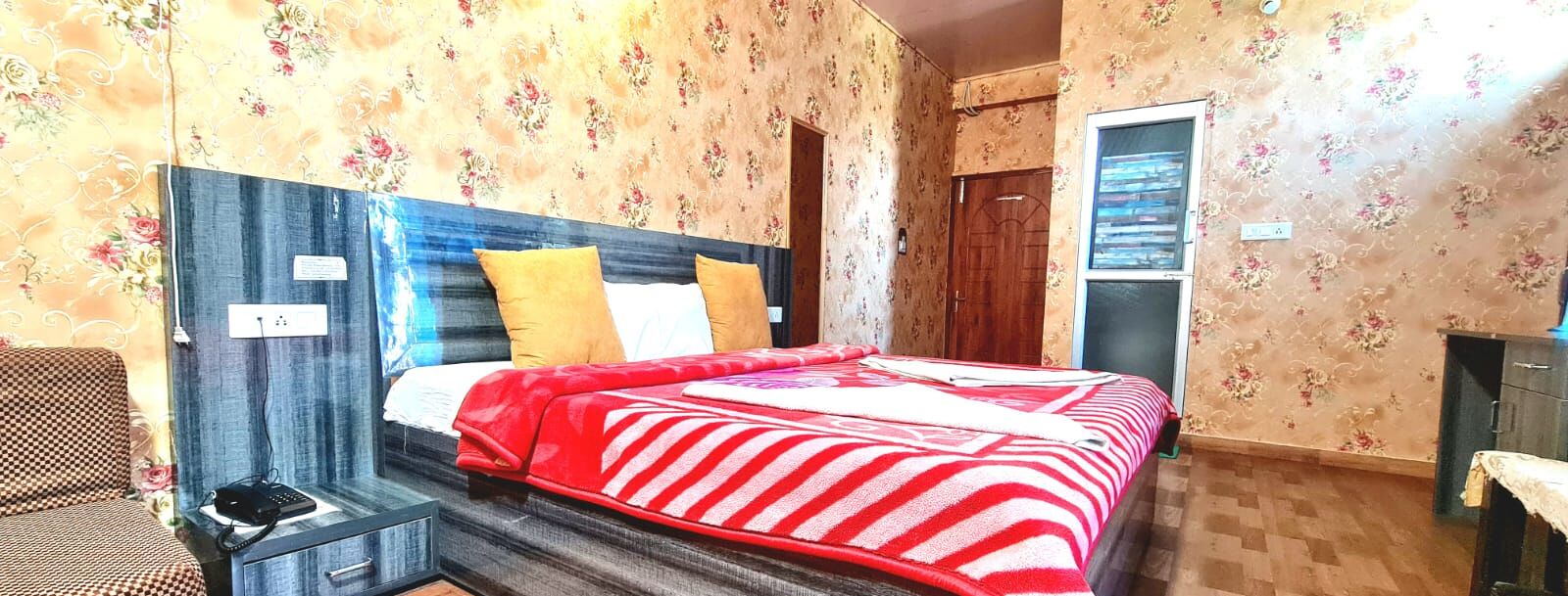 Um quarto com uma cama, mesa de cabeceira, telefone e guarda-roupa.