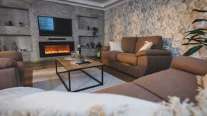 Una sala de estar moderna con chimenea, asientos cómodos y una televisión.