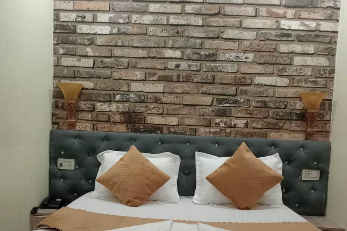 A bed with a tufted headboard, two bedside lamps, and a brick-patterned wall behind it.