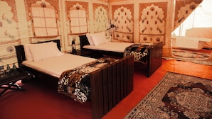 A traditional room with two beds, ornate wall decorations, and a large rug. - Shivika Lake Hotel Ranakpur (Desuri)