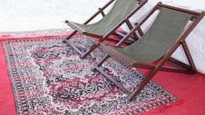 A tent with two wooden-framed chairs and a patterned rug on the floor. - Shivika Lake Hotel Ranakpur (Desuri)