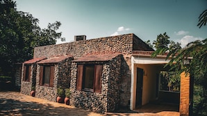 A stone building with a tiled roof, potted plants, and a paved entrance. - Shivika Lake Hotel Ranakpur (Desuri)