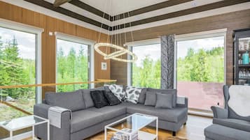 A modern living room with a sectional sofa, a glass coffee table, and a fireplace.