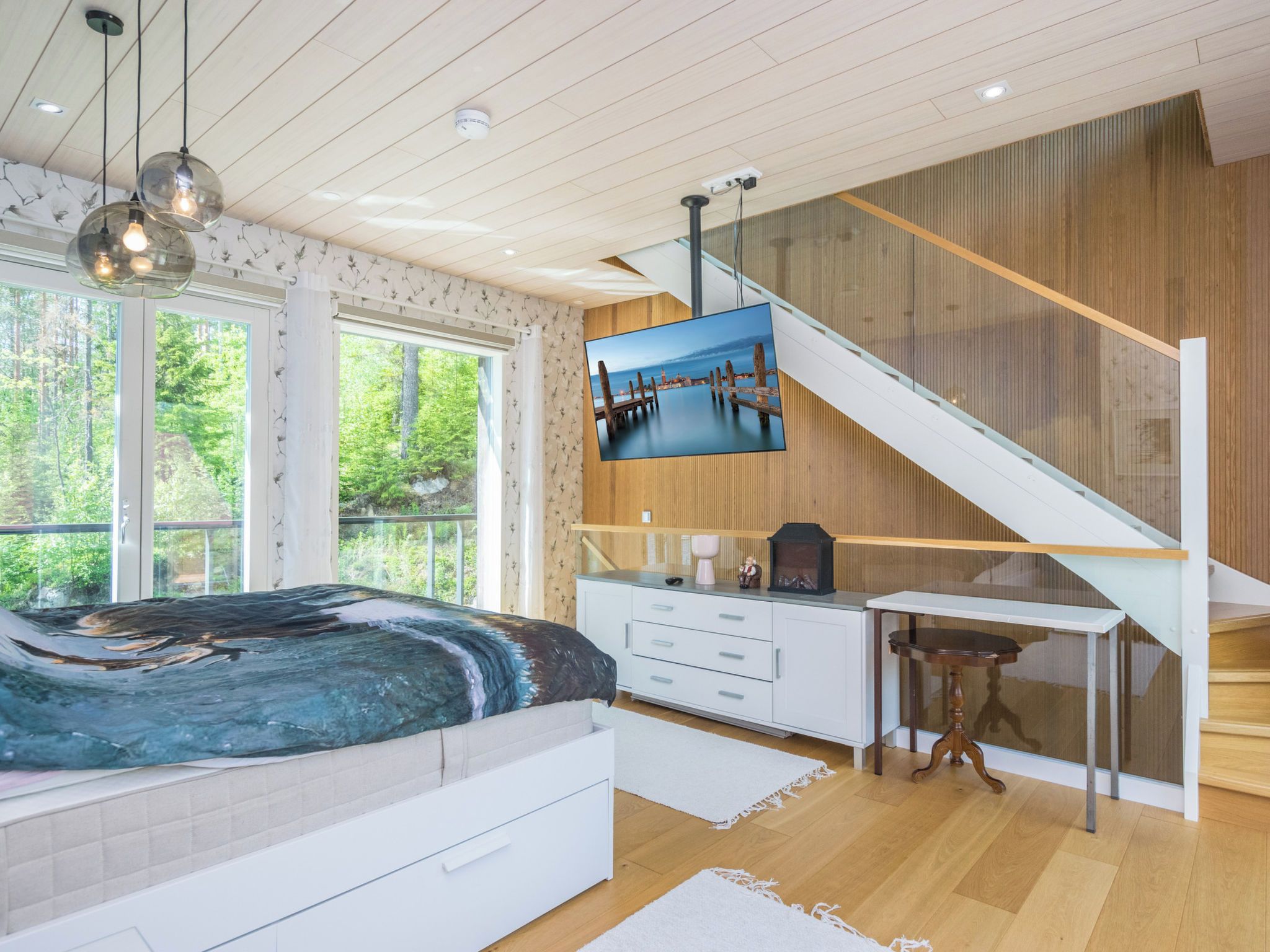 A bedroom with a bed, a desk, and a TV mounted on the wall.