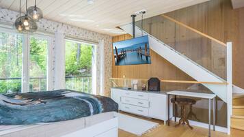A bedroom with a bed, a desk, and a TV mounted on the wall.