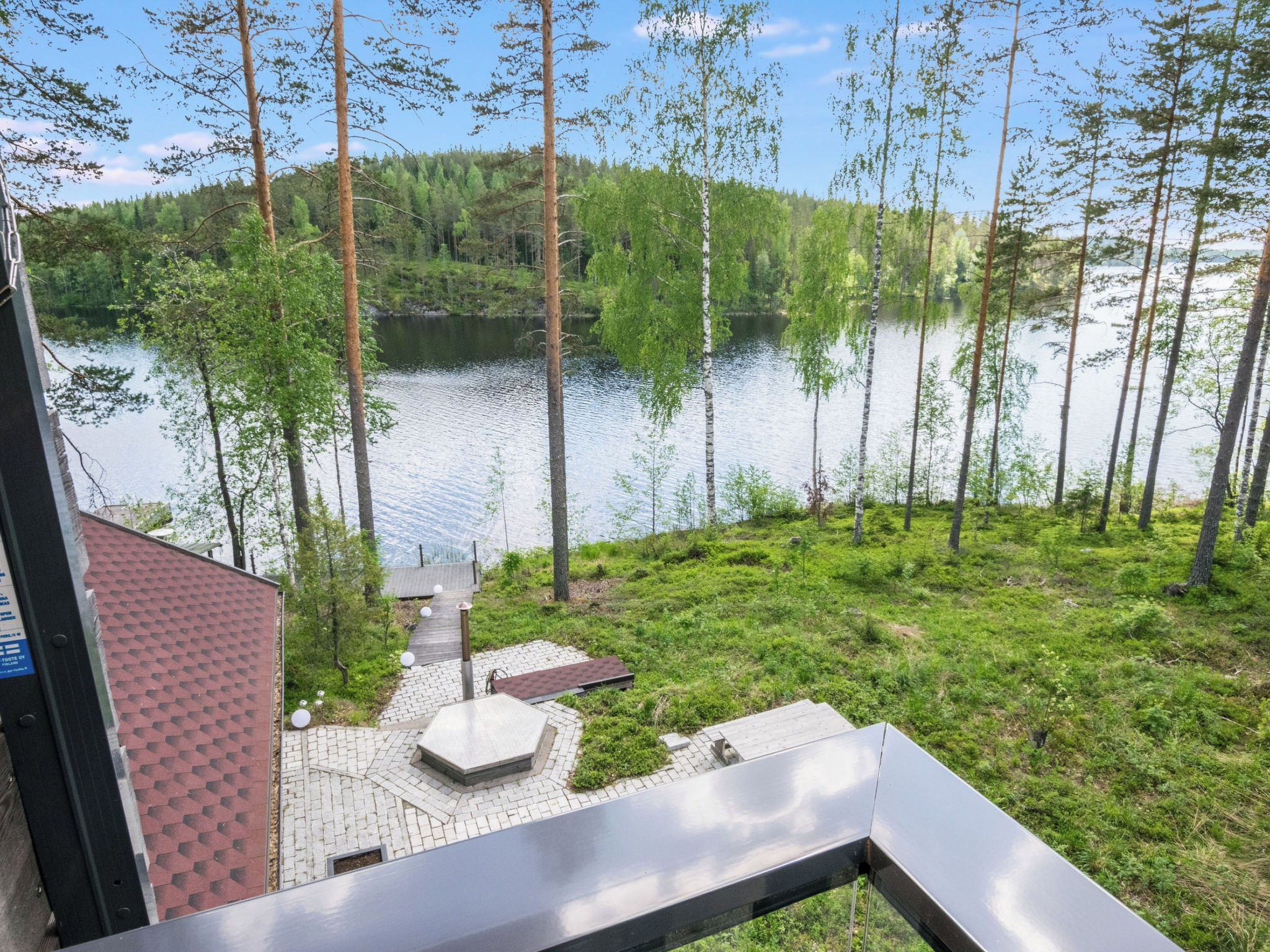 A lakeside view with a wooden deck and a building with a red roof.