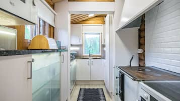 A compact kitchen with a wooden ceiling, a window, and a built-in stove.