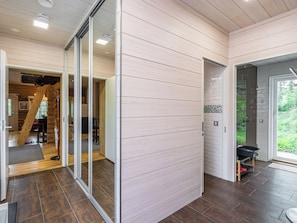Un intérieur moderne avec un plancher en bois, une porte vitrée donnant sur une pièce dotée d’une cheminée, et une vue sur la verdure à l’extérieur.