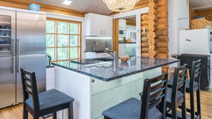 A modern kitchen with a central island, stainless steel appliances, and a chandelier.
