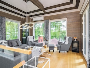 Un salon moderne doté d’une cheminée, de grandes fenêtres et d’un coin salon confortable.