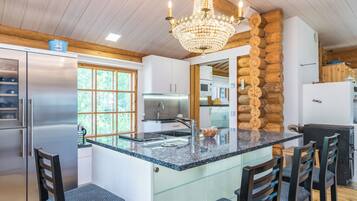 A modern kitchen with a large island, stainless steel appliances, and a chandelier.