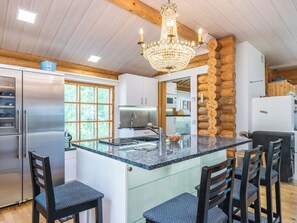 Une cuisine moderne dotée d’un grand îlot central, d’appareils électroménagers en acier inoxydable et d’un lustre.
