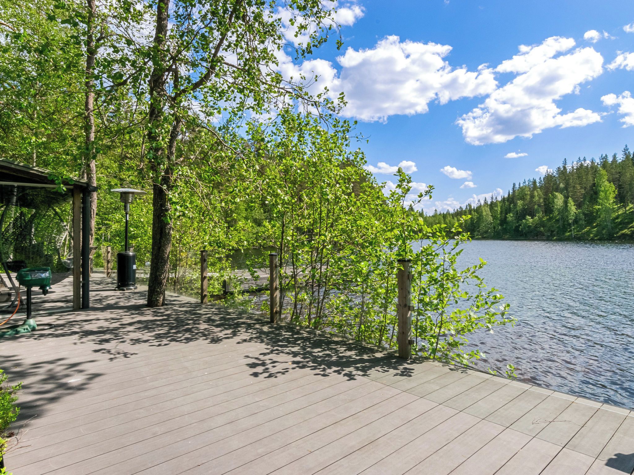 Een houten terras met uitzicht op een meer en bos.