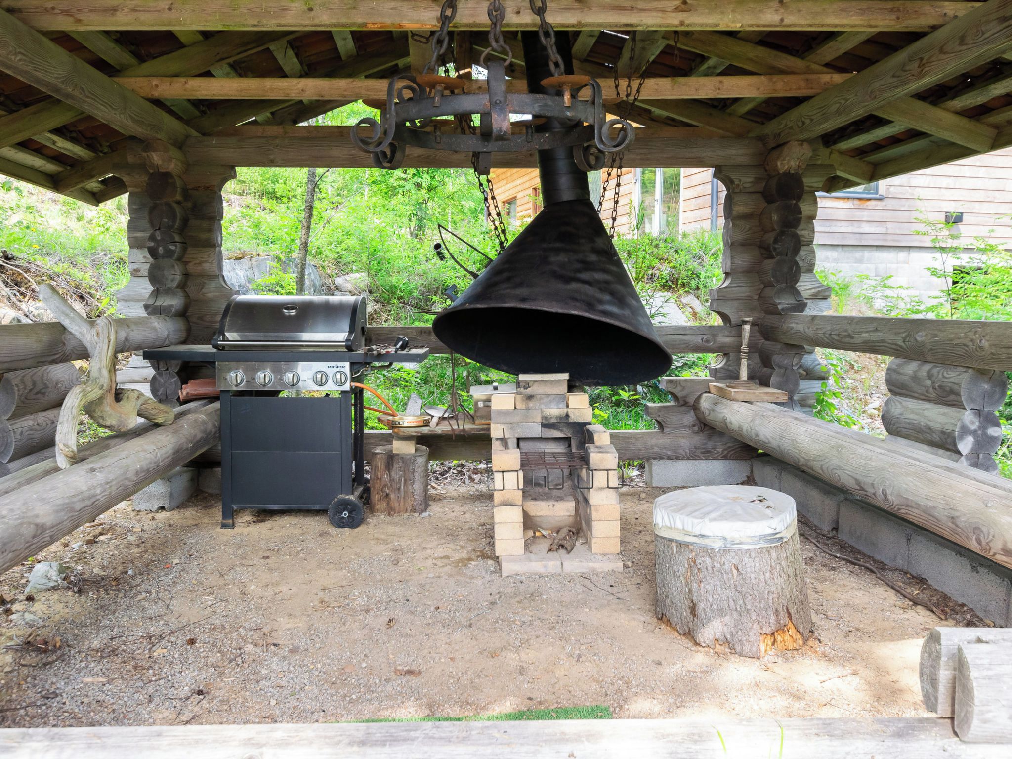 Un espace barbecue extérieur équipé d’un gril, d’une cloche et d’un four en pierre.