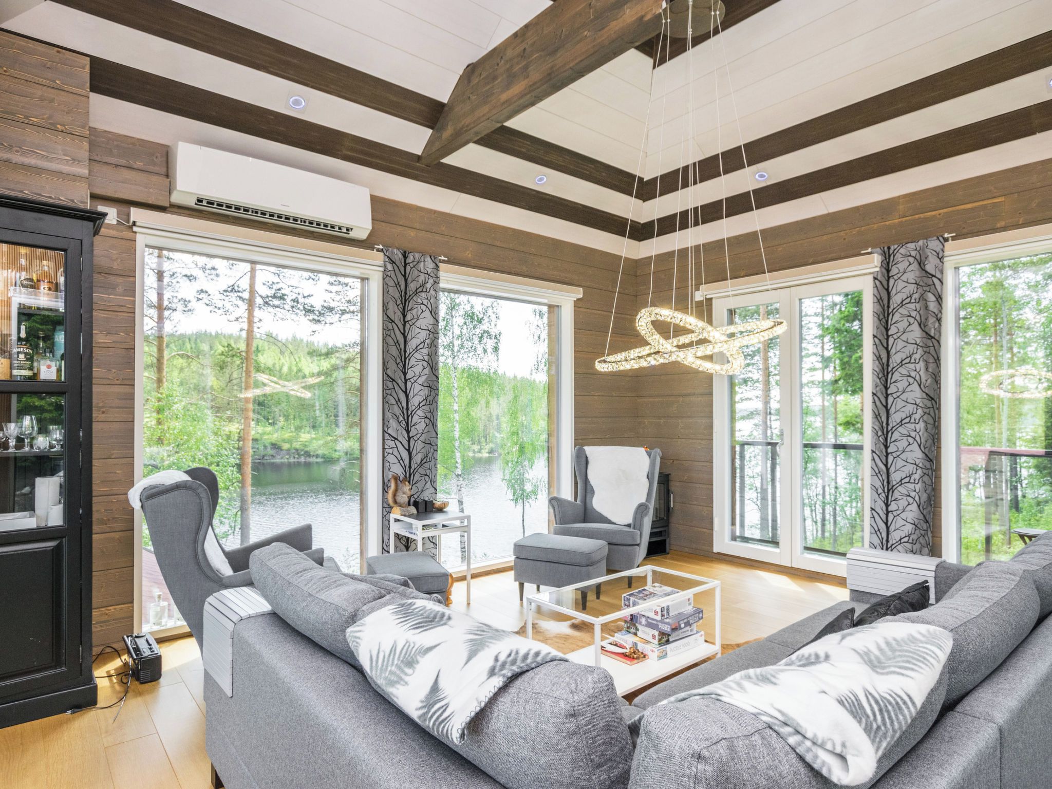 A modern living room with a fireplace, large windows, and a view of the outdoors.