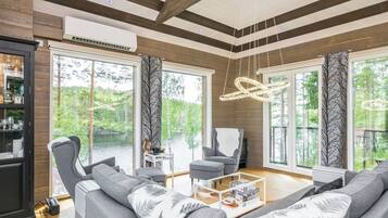 A modern living room with a fireplace, large windows, and a view of the outdoors.