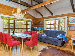 A rustic interior with a dining area, a sofa, and a chandelier.