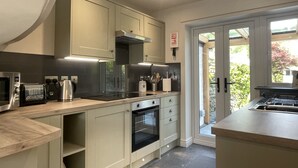 Una cocina moderna con electrodomésticos integrados, un ventanal grande y una puerta que da a un balcón.