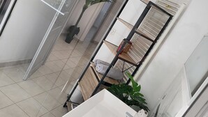 Moderni kylpyhuone, jossa on valkoinen pesuallas, pyyhekoukku ja ruukussa oleva kasvi.