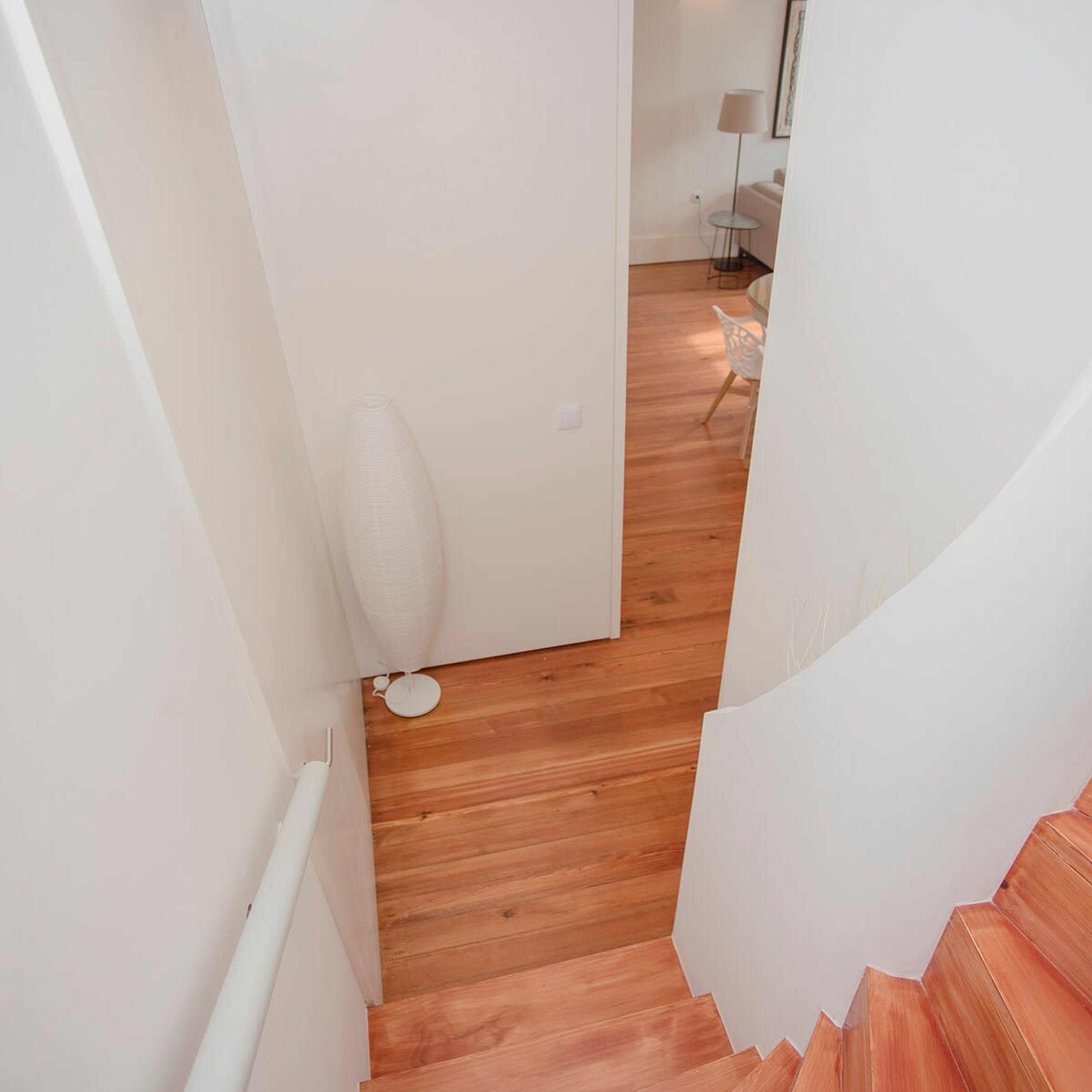 A narrow staircase with wooden steps leading to a room with a white door.