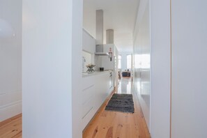 Une cuisine moderne avec des meubles blancs, un plancher en bois et un tapis noir qui mène à un coin repas.
