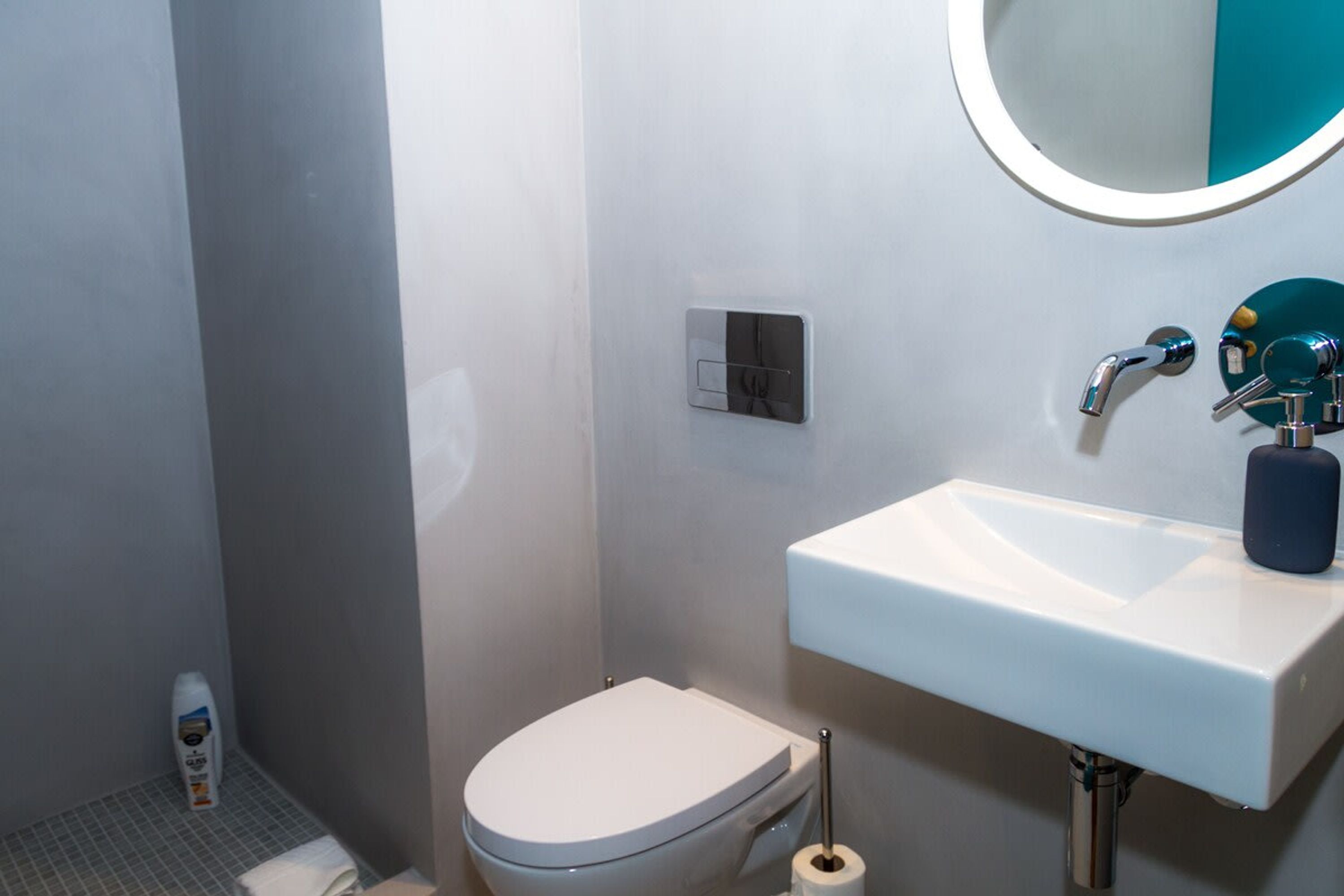 A bathroom with a toilet, sink, and mirror.
