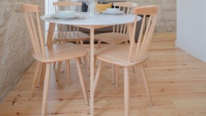 Un coin repas avec une table ronde, six chaises en bois et un mur en pierre.