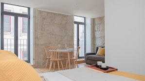 Een moderne hotelkamer met een groot bed, een eettafel met stoelen, een bank en een stenen muur.