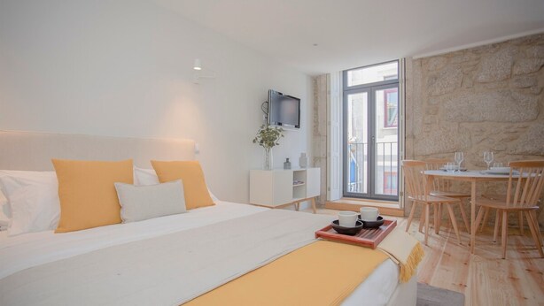 Een moderne hotelkamer met een groot bed, een zithoek met houten meubels, en een stenen muur.