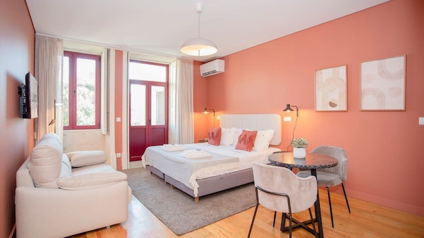 Ein modernes Schlafzimmer mit Bett, einer Couch, einem Esstisch und Stühlen.