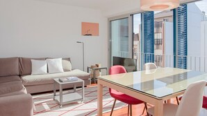 Un salon moderne avec une table à manger en verre, un canapé et une petite table d’appoint.