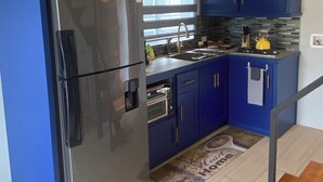 Une cuisine moderne avec des armoires bleues, un réfrigérateur en acier inoxydable, une cuisinière à gaz et un four encastré.