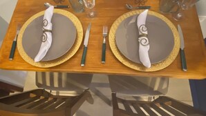 Une table à manger dressée avec deux assiettes, des couverts et des verres.