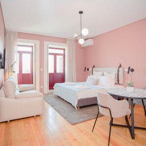 Une chambre à coucher moderne avec un lit, un canapé, une table à manger et un luminaire au plafond.