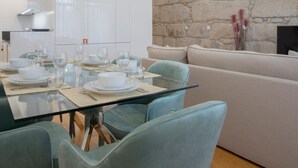 Ett modernt matområde med ett glasbord, ljusblå stolar och en accentvägg i sten.