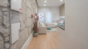 Ein modernes Wohnzimmer mit Steinwand, einer Sofagarnitur und einem Essbereich mit Glastisch.