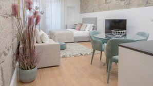 Ein modernes Wohnzimmer mit einer Wand aus Stein, einer Couch, einem Esstisch mit Stühlen und einem Kamin.