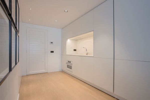 A modern kitchen with white cabinetry, a built-in oven, and a countertop with a sink. - Liiiving in Gaia - Beach Seaside Apartment (Vila Nova de Gaia)