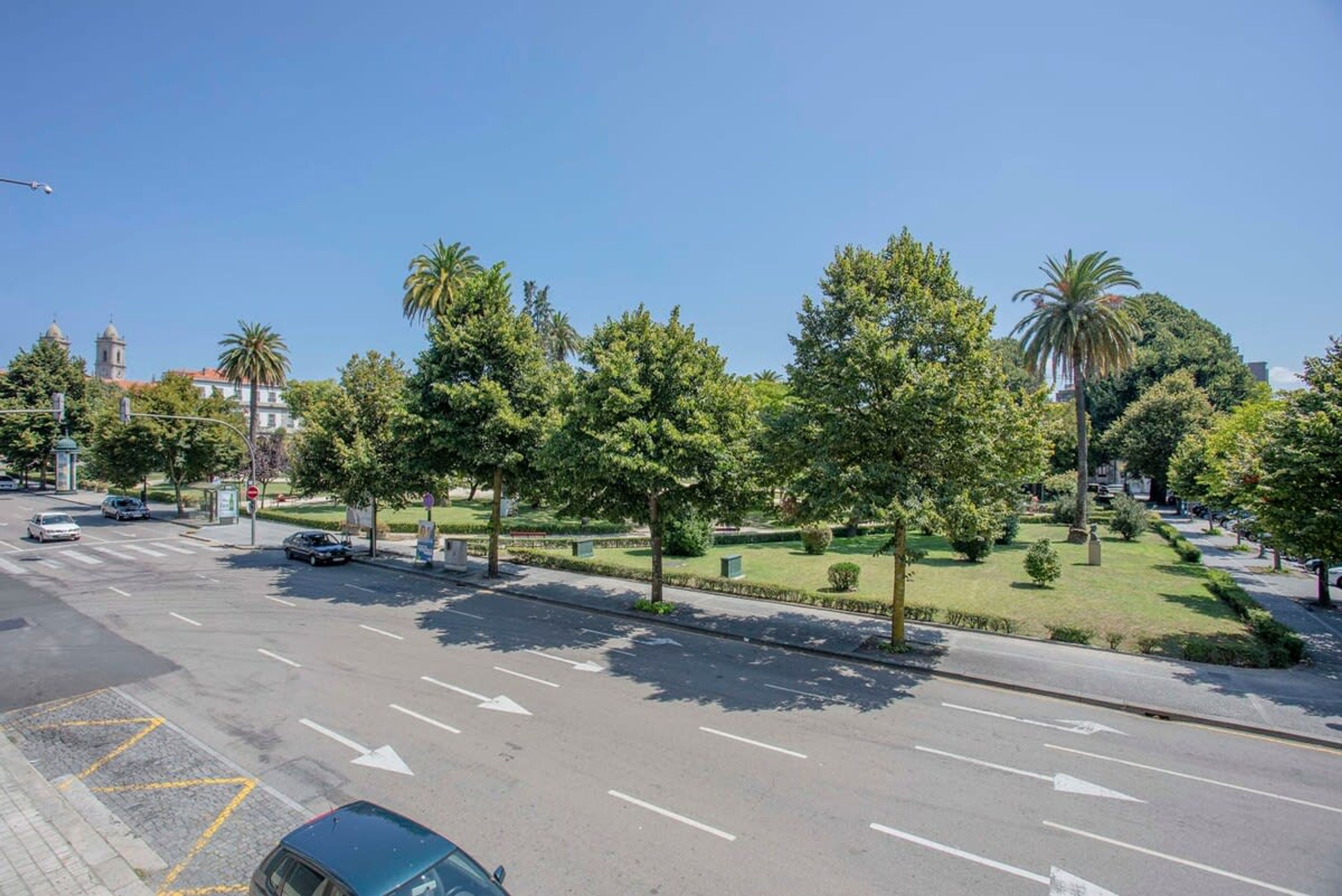 A street with a clear road, marked lanes, and a green median with trees.